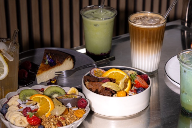 Tisch mit Iced Matcha, Cold Brew, Basque Cheesecake und Açaí-Bowl